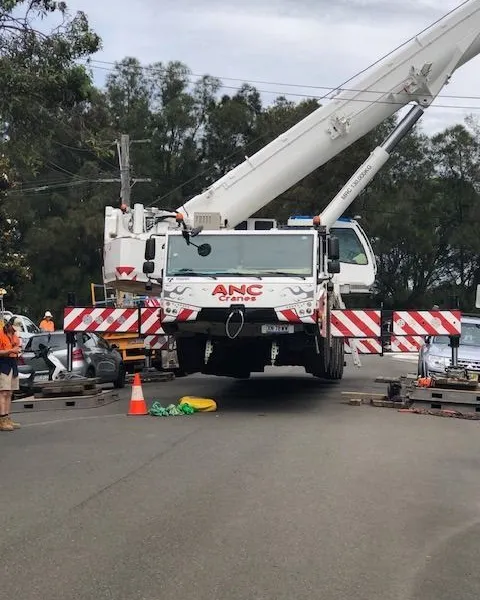 Large crane truck set up on a closed suburban street with traffic control